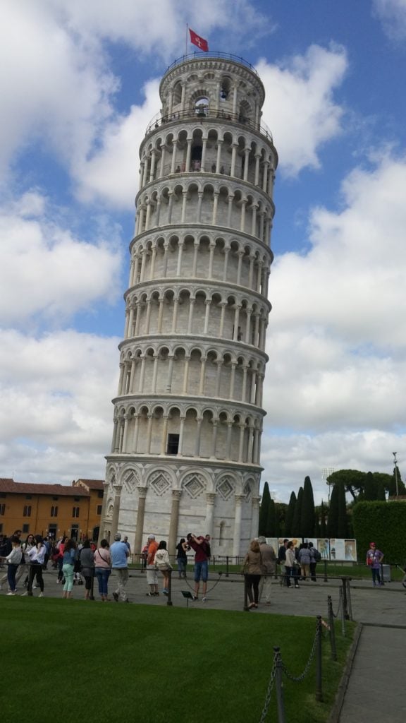 View of the Leaning Tower of Pisa from the ground, with a blue sky with clouds in the background