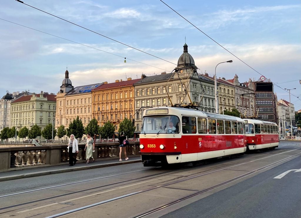 A red and white tram crossing a bridge in Prague.