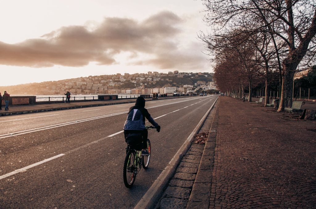 A lone cyclist bicycling along the Naples waterfront.