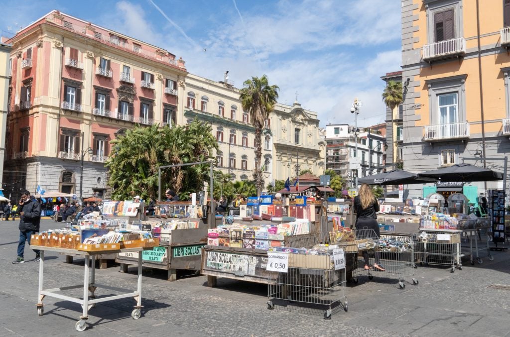 An outdoor market in Naples with piles of used books on tables.
