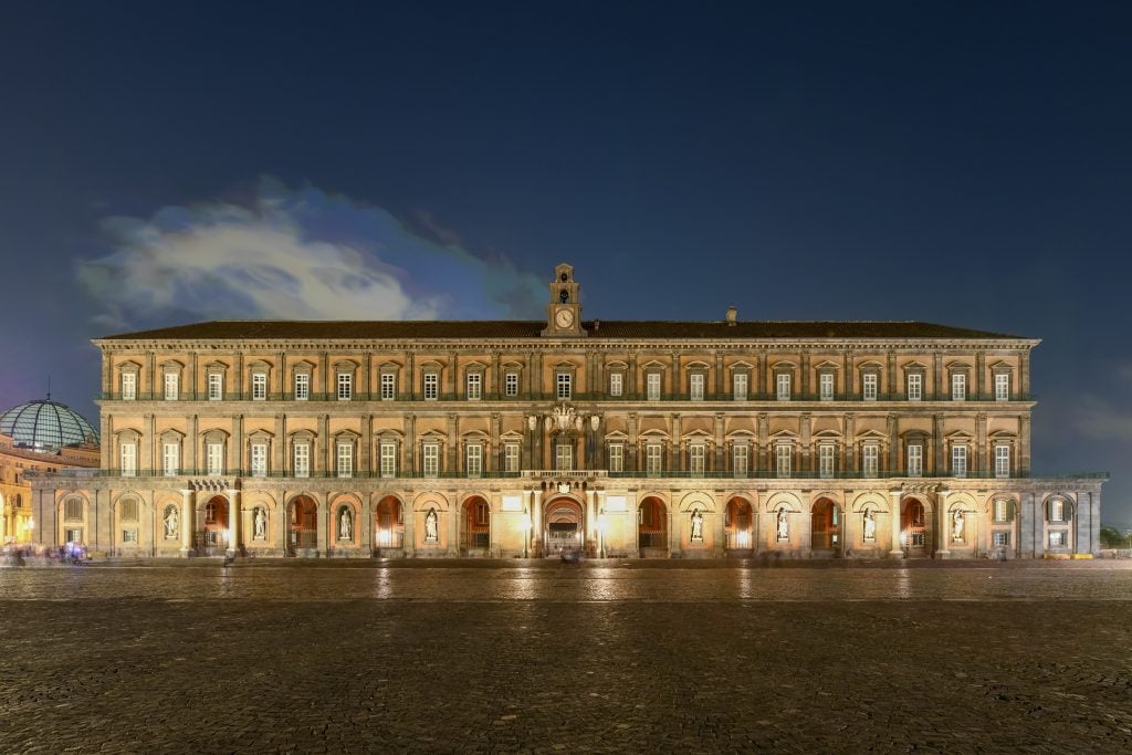 A long, rectangular building illuminated in every window, standing out against the dark night sky.