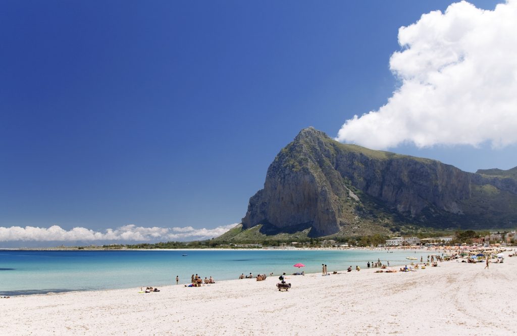 A white sand beach with blue water on a clear day in San Vito Lo Capo, one of the best places to visit in Sicily