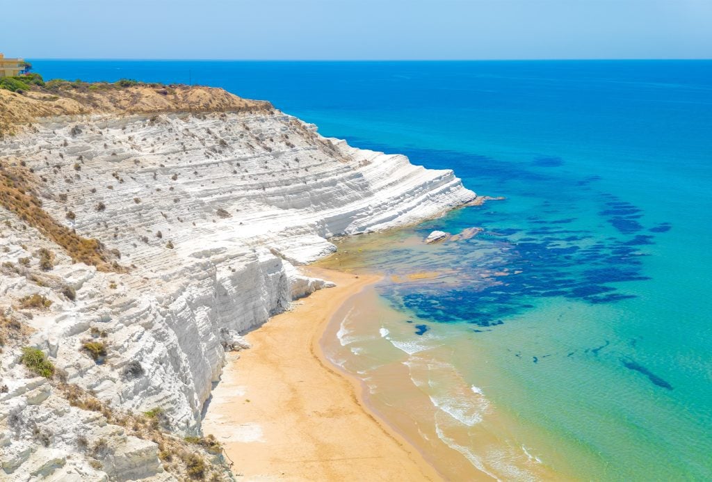 Aerial view of the coastline along Scala dei Turchi, with golden sand and blue water