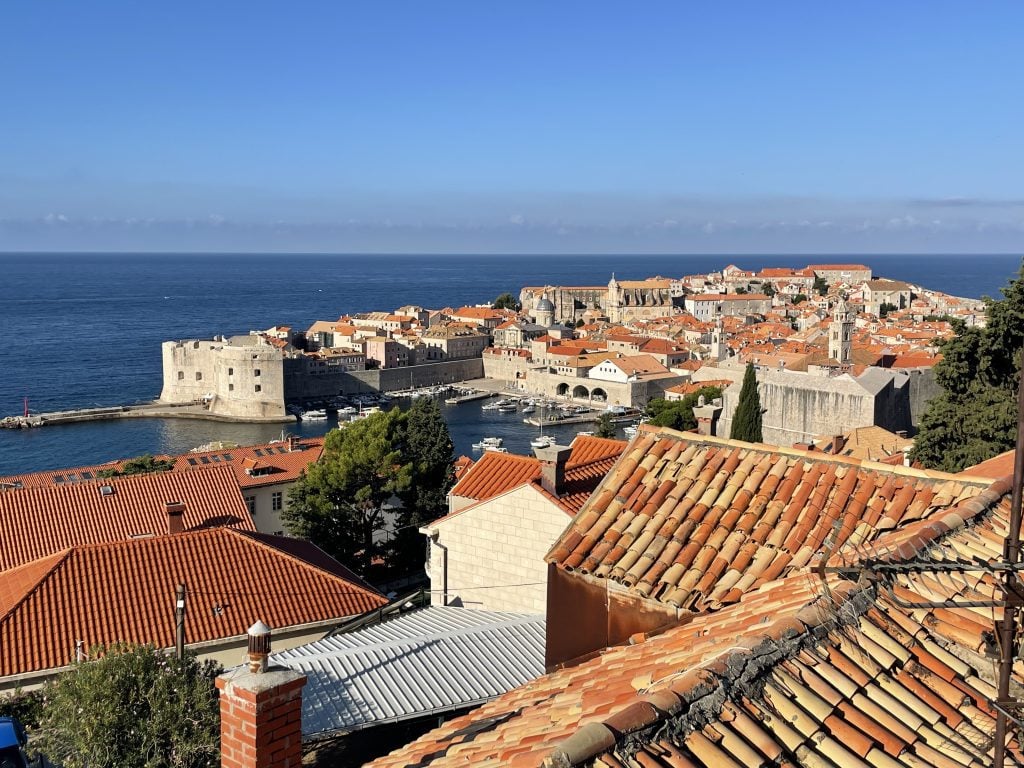 Dubrovnik's old city, with orange roofs and surrounded by a big wall, set in the sea.