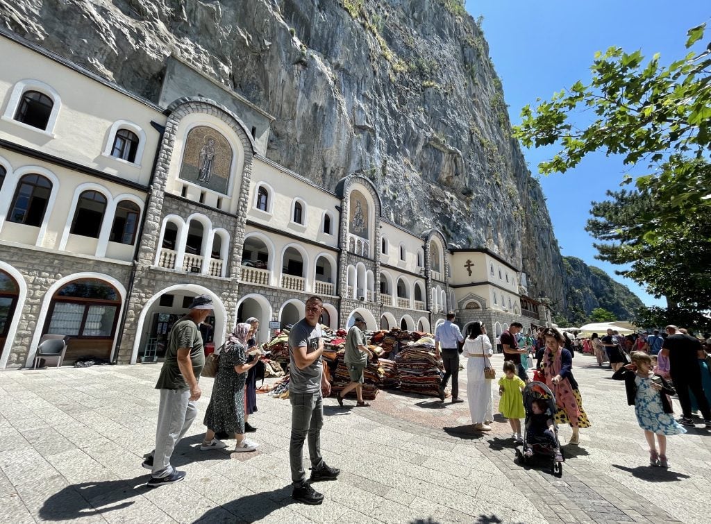 People waiting in line at a monastery carved into the wall of a cliff.