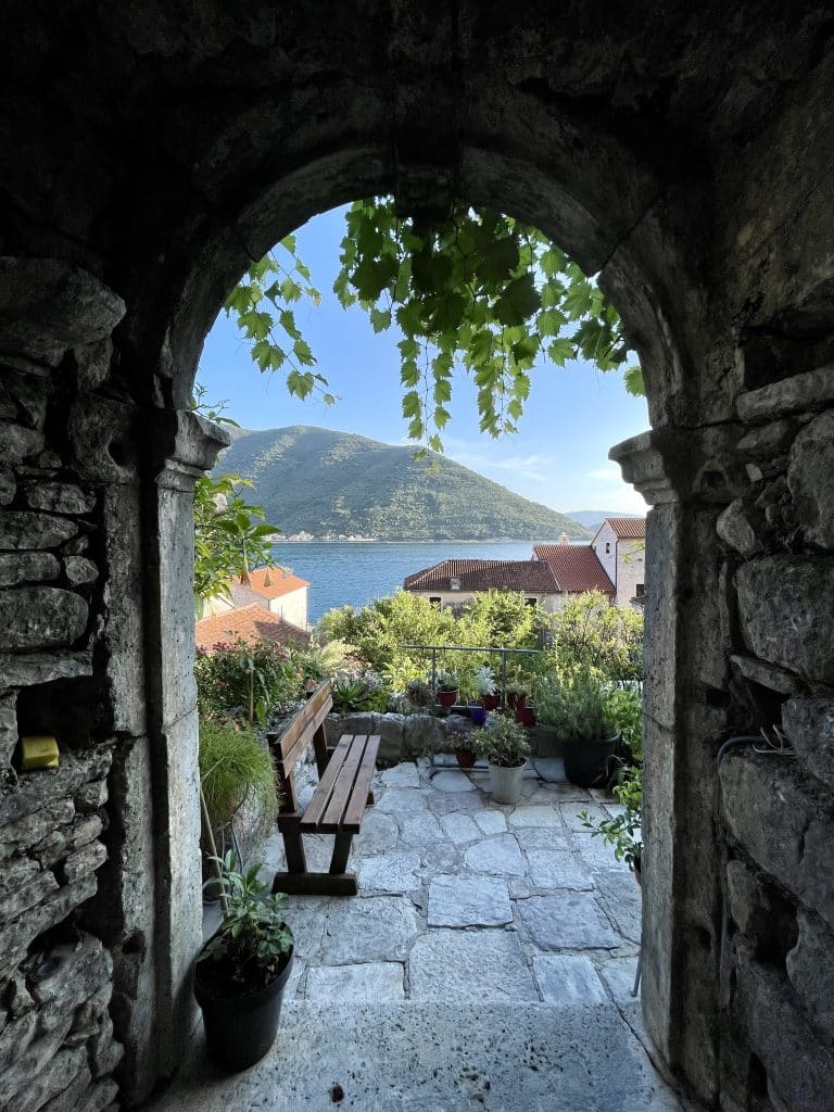 A doorway leading to a gorgeous fjord view and lots of plants in Montenegro.