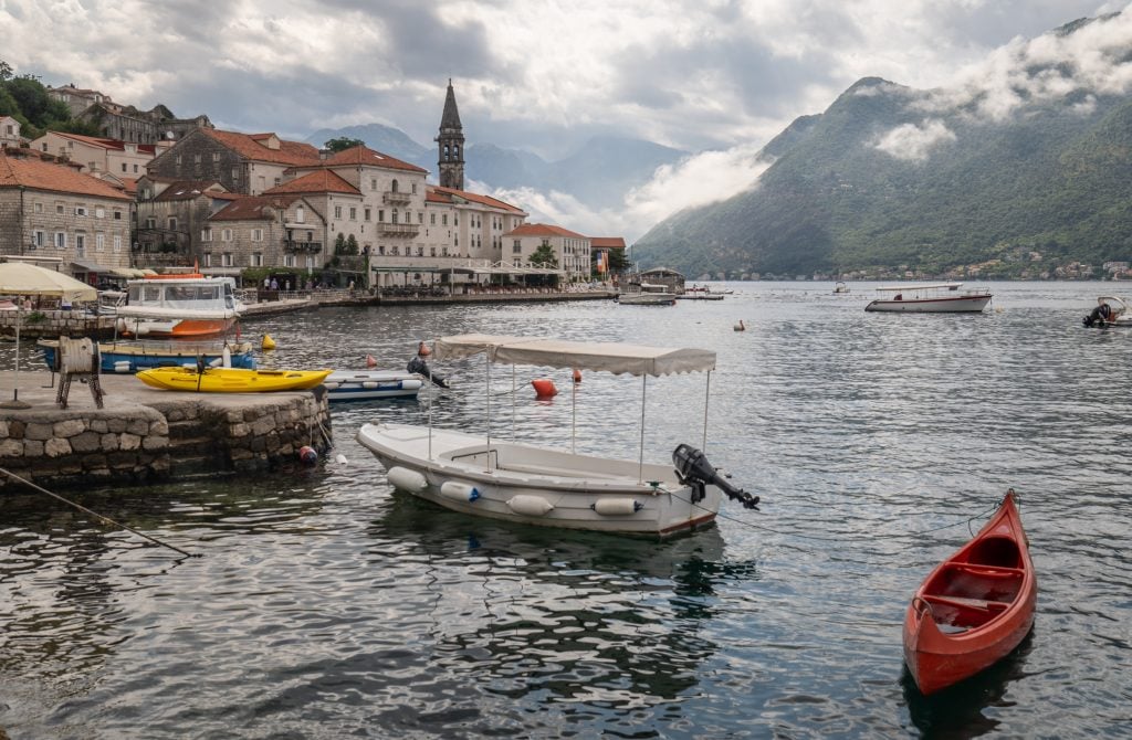The tiny town of Perast, set on the bay of Kotor on a cloudy rainy day, lots of boats in the gray water.