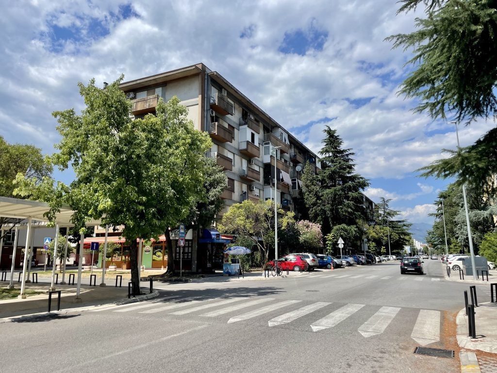 A nondescript city block with a communist-era cement block apartment building.