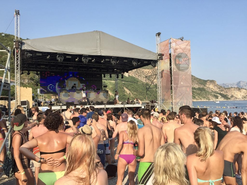 People in swimsuits watching a concert on the beach.