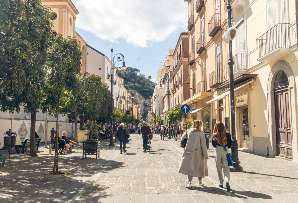 Two women walking down a cobblestone street surrounded by pastel buildings in Sorrento Italy