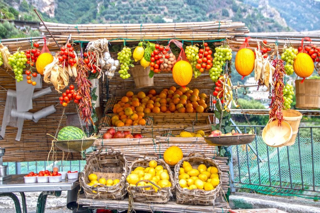 A roadside stand in Italy with lots of bright red tomatoes and bright yellow lemons.