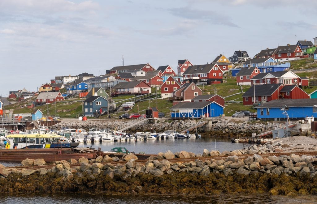 The town of Aasiaat, Greenland, with colorful houses built on a rocky cliff overlooking the bay.