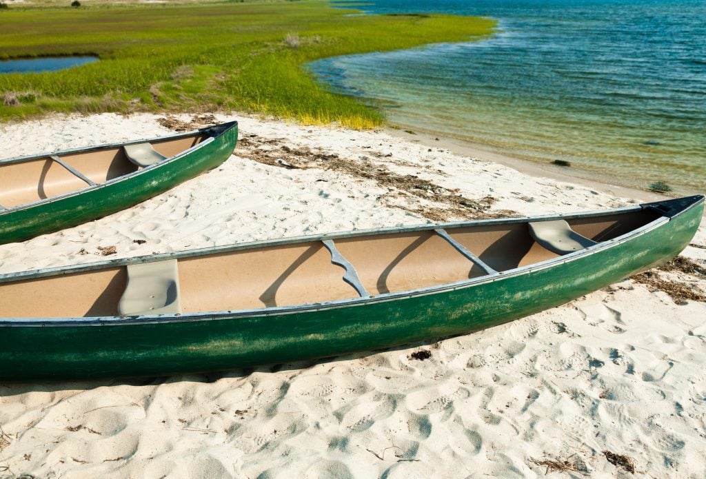 Two green wooden canoes perched on the beach on Chappaquiddick Island.