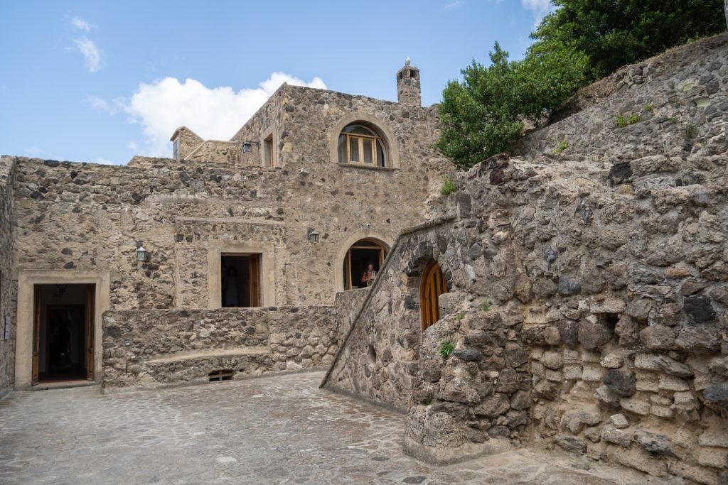 The interior of a stone castle, with lots of high walls and arched windows.