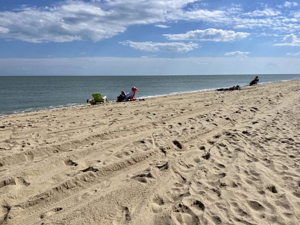 People sitting in beach chairs on a long stretch of sand in Martha's Vineyard.