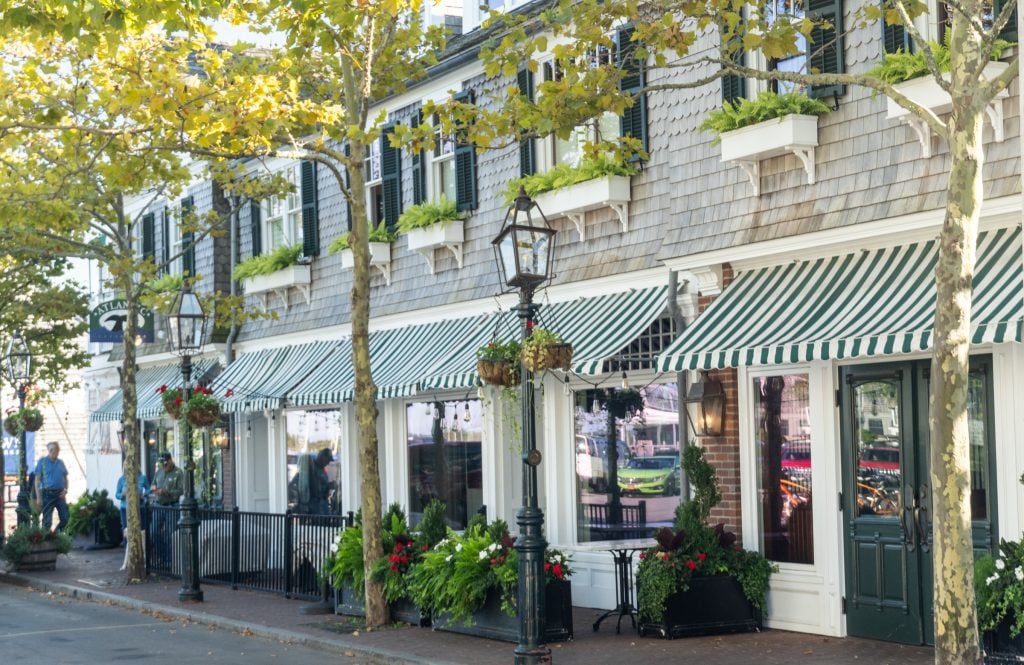 A quiet street lined with boutiques, each of them with overhanging green and white-striped awnings.