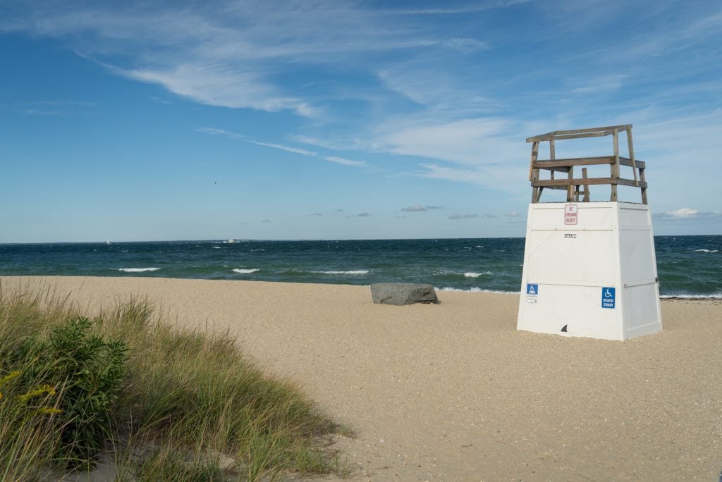 An empty sandy beach in Martha's Vineyard, an empty lifeguard's stand looking over the water.
