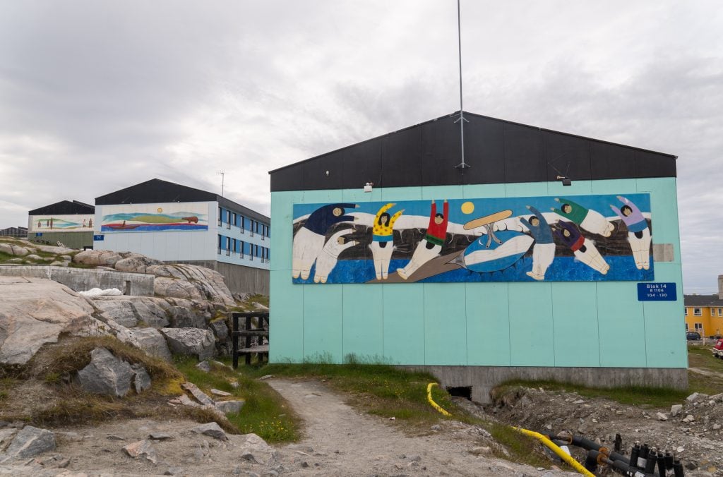 The side of a house emblazoned with an Inuit mural of people dancing.