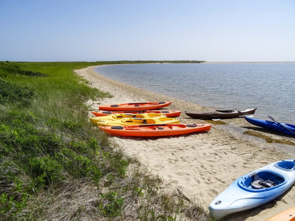 Kayaks lying on the beach on the edge of a pond in Martha's Vineyard.