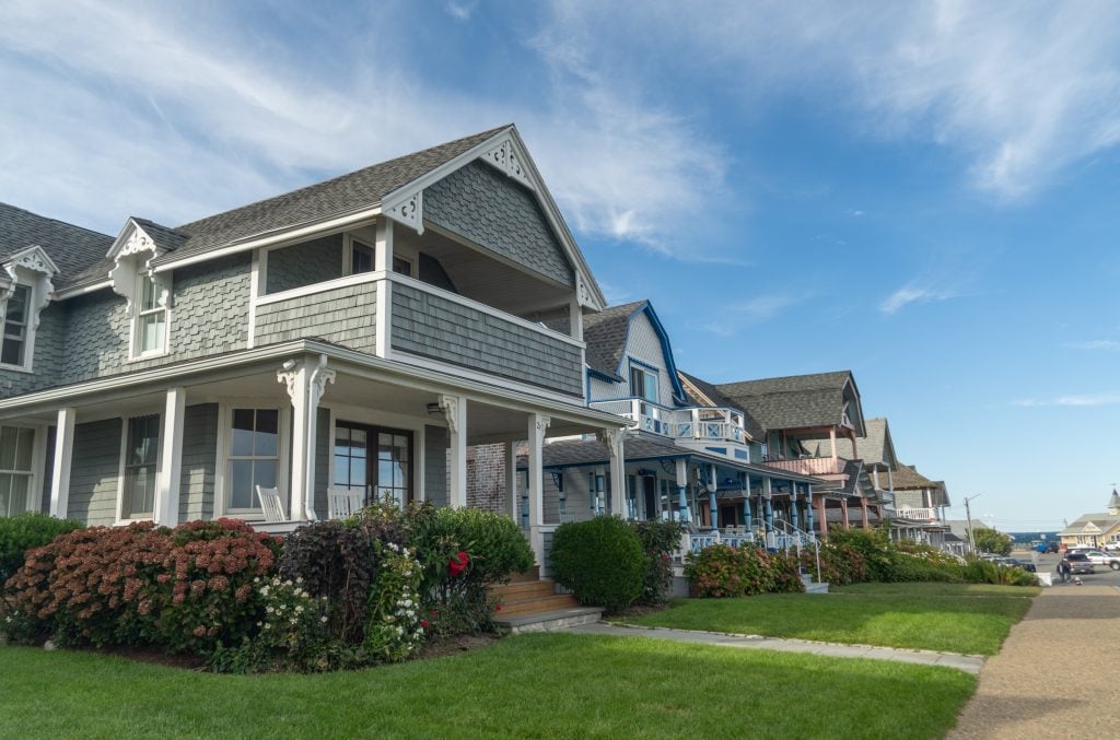 A row of elegant Victorian houses with well-manicured rhododendron bushes in Martha's Vineyard.