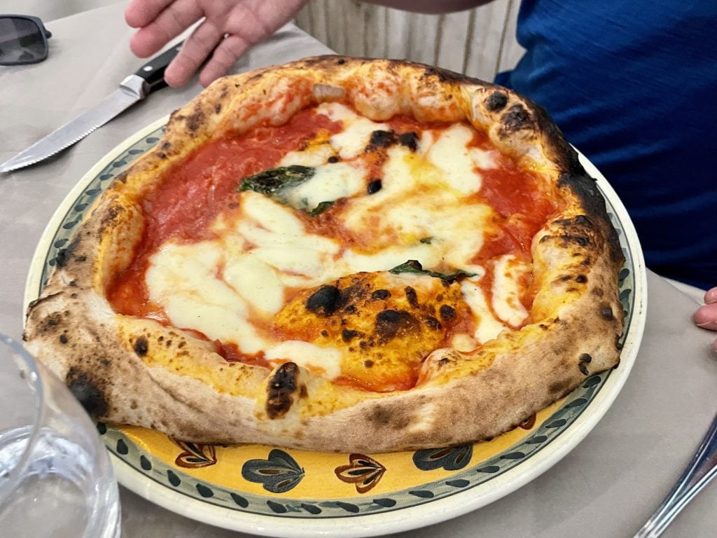 A perfect Neapolitan pizza with a bubbled-up crust and lots of cheese, sauce, and basil leaves.
