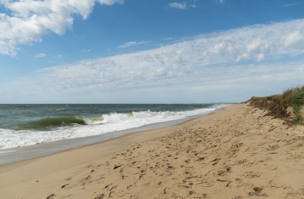 A long stretch of sandy beach with big, crashing waves.