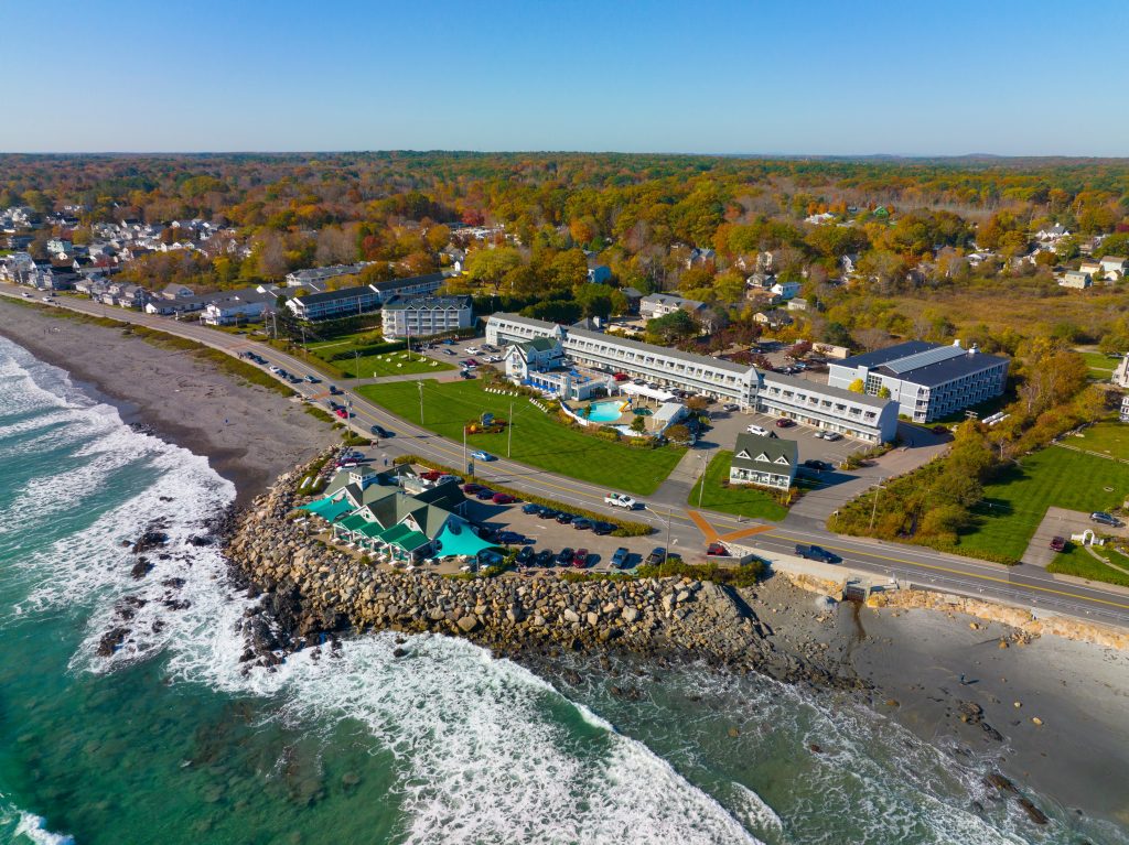 A resort on the edge of the beach in Maine, wild waves crashing on the shore.