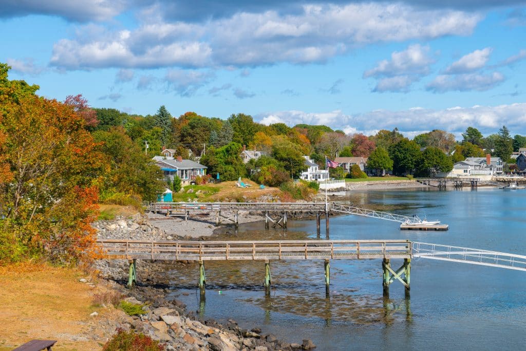 A small seaside village in Maine, cottages on shore, wooden docks leading out to the water.