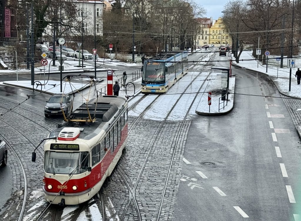 A tram going down the street in Prague on a snowy day.