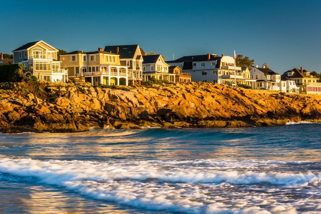 A row of mansions on the Maine coast, all lit up with bright sunlight right before sunset.