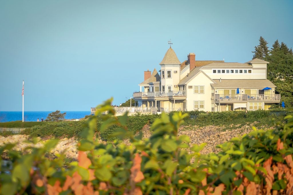 A hiking path winding past an enormous mansion perched on the edge of the sea in Maine.