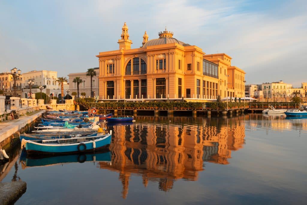 A big read theater on Bari's coastline, reflecting in the harbor.