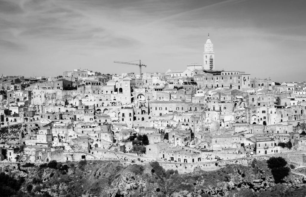 The belvedere (view of Matera) with layers of stone buildings and a church steeple, in black and white.