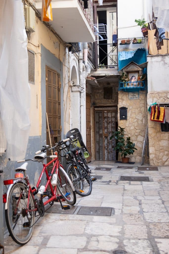 A quiet street in Bari with an altar to the Virgin Mary and some bicycles parked.