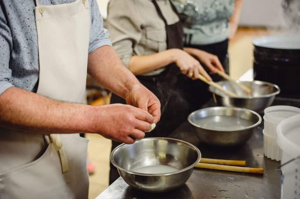 People in a cooking class making something in metal bowls.