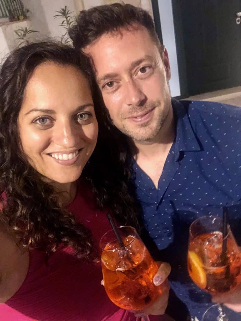 Kate and Charlie taking a smiling selfie with aperol spritzes.