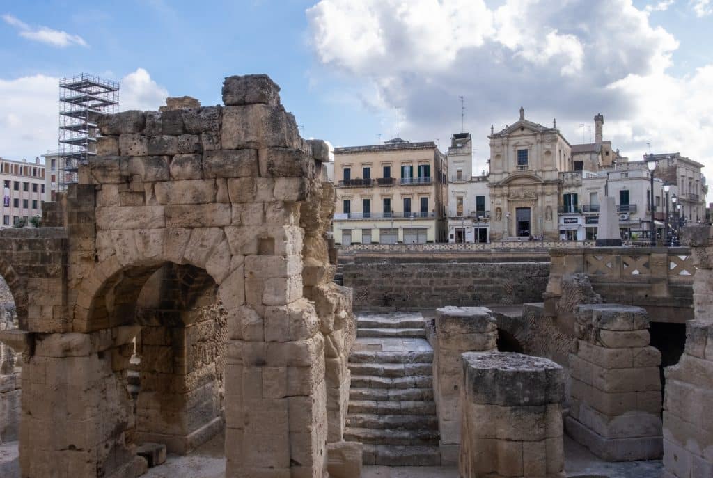 Modern buildings in Lecce, with huge stone ruins in front, obscuring their view.