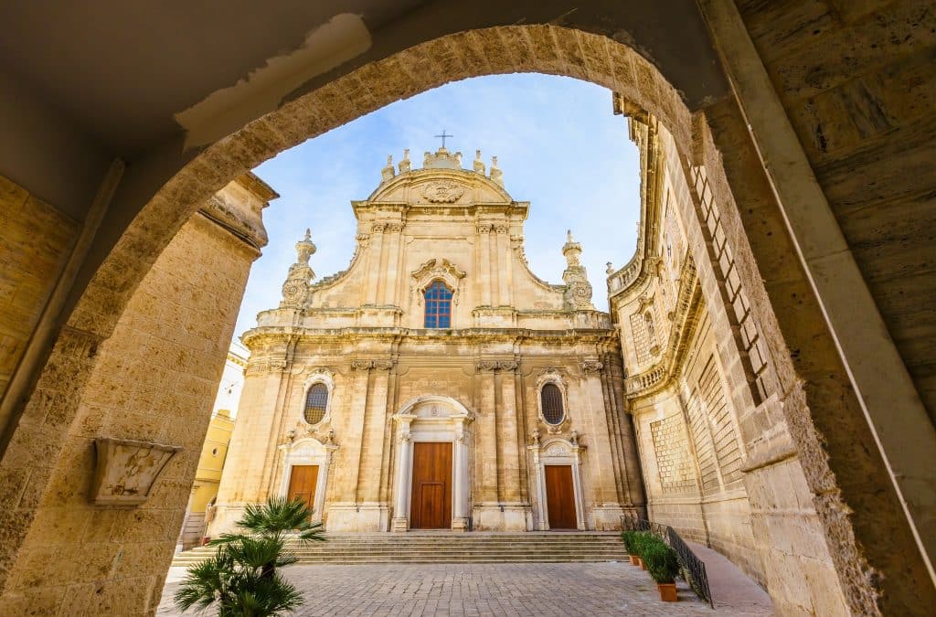 A tall, sand-colored Baroque cathedral in Monopoli, Italy.