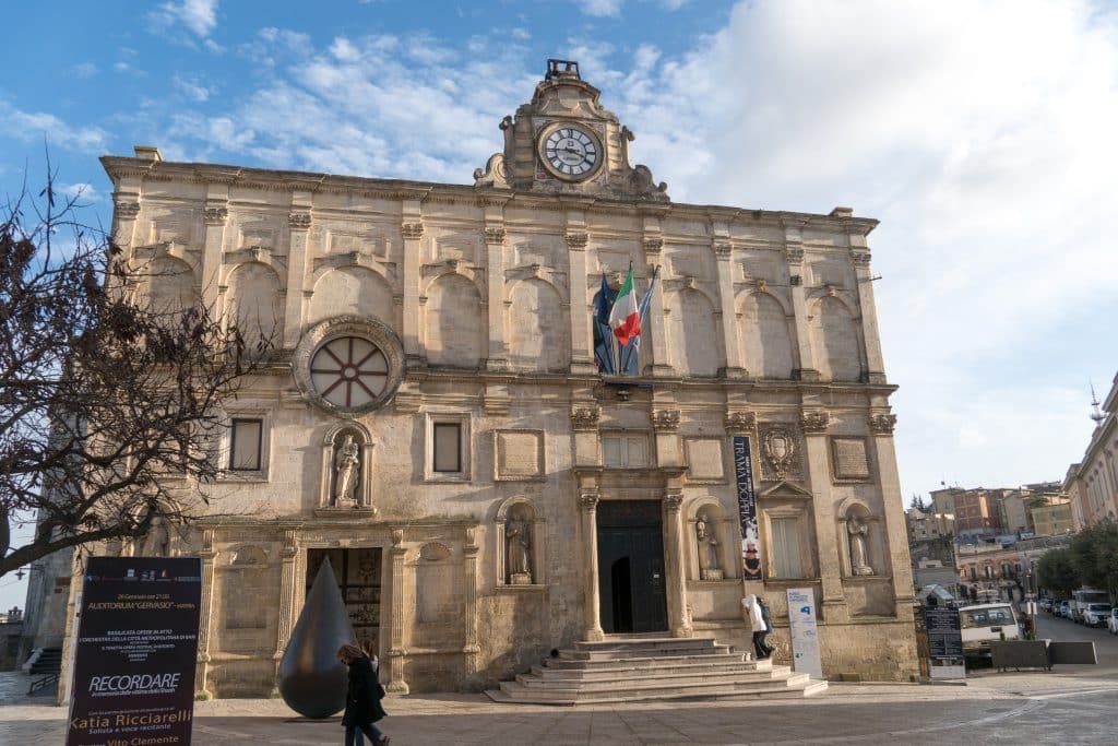 A tall museum in Matera, with a clock perched on top of the building.