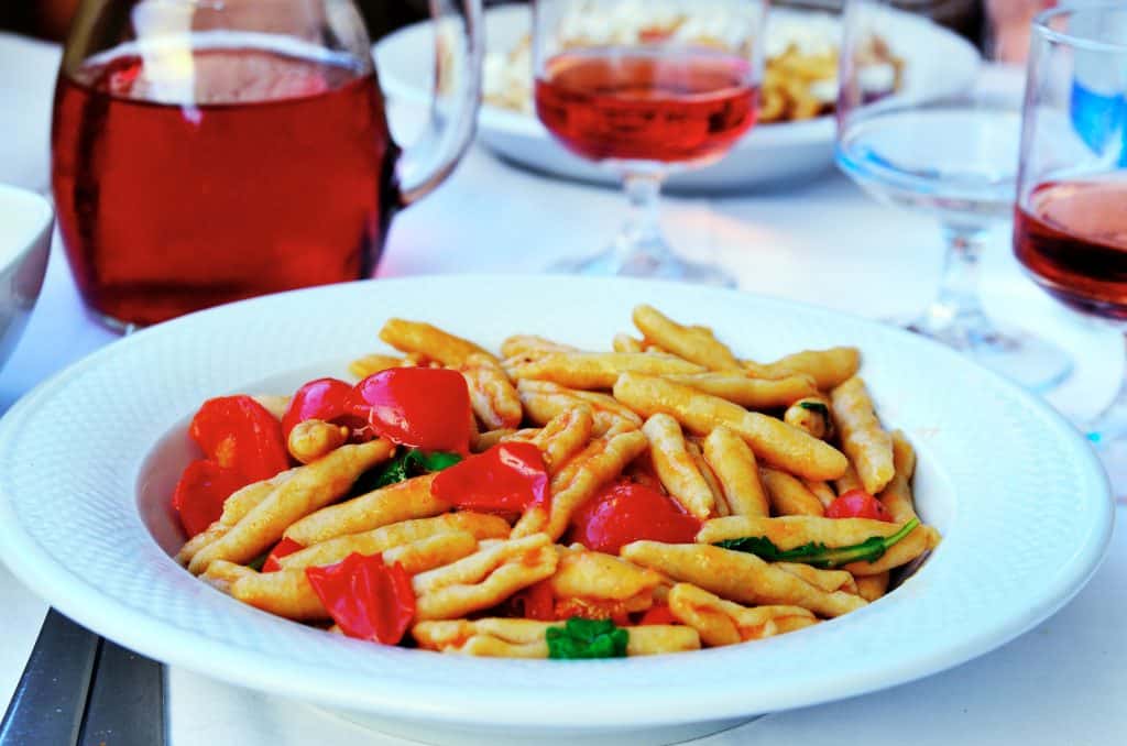 A bowl of cavatelli pasta with tomatoes and basil.