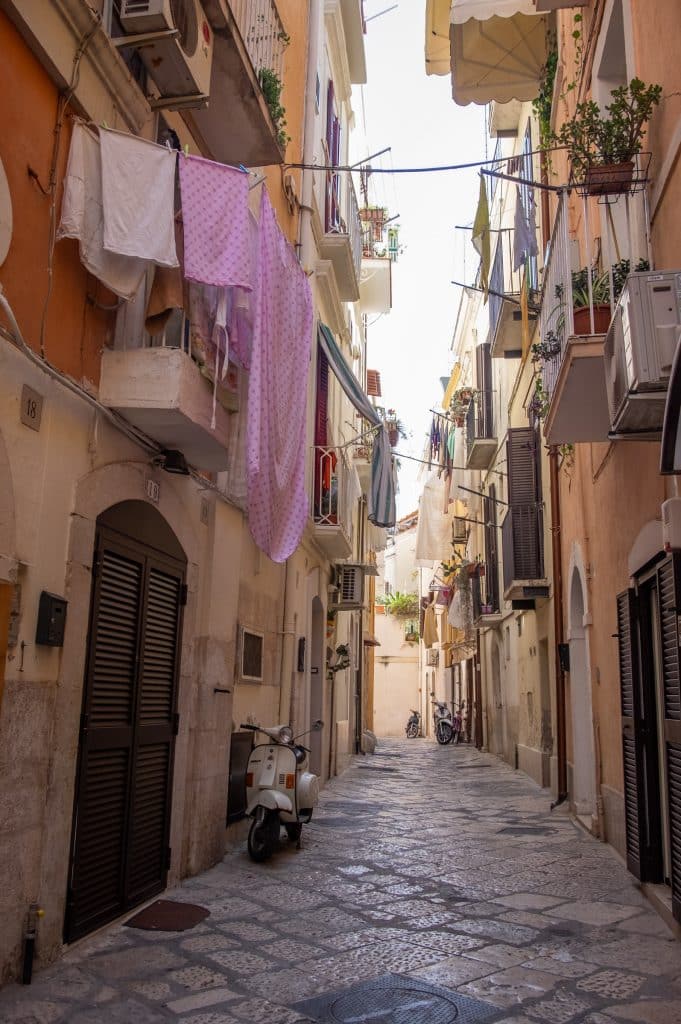 Laundry hanging on a line strung between two balconies on a quiet street in Italy.