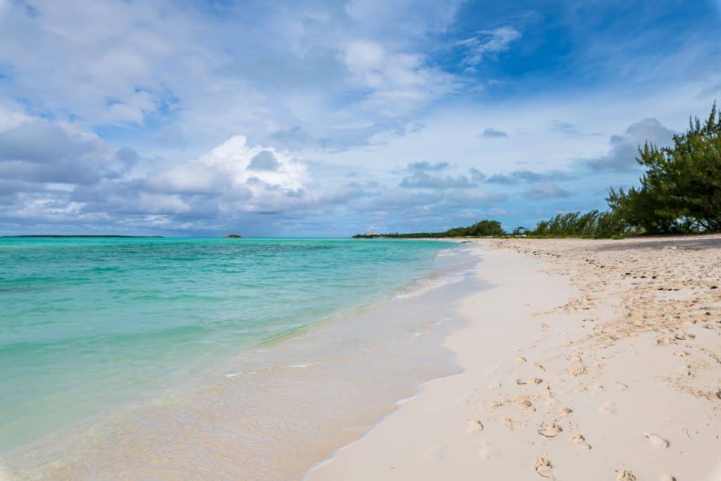 A calm white sand beach on a bright turquoise sea.