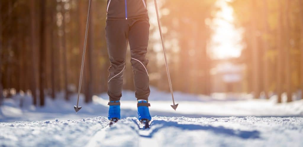 A woman cross-country skiing through the woods.