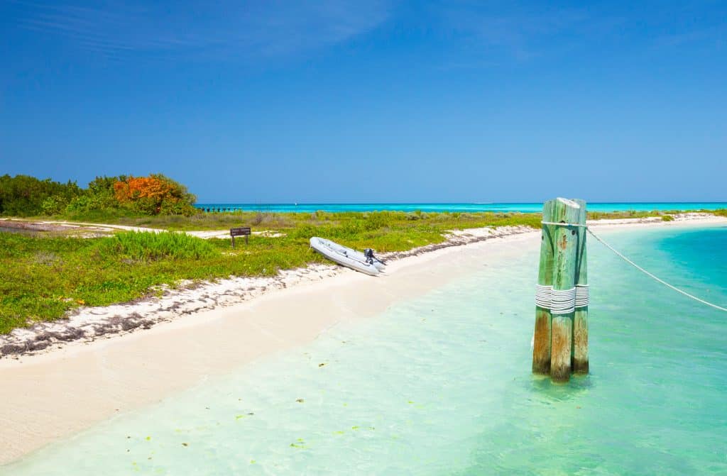 A very calm white sand beach with clear aquamarine water.