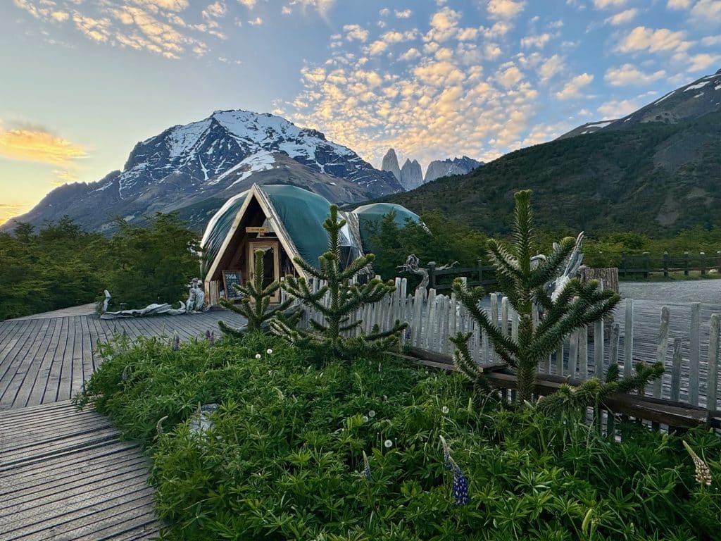 Dome-style buildings in Patagonia, with mountains and a sunset rising up in the background.