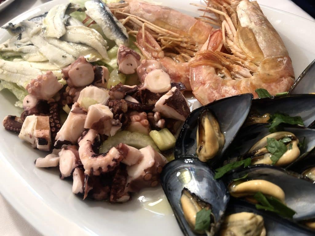 A plate of mussels, octopus, anchovies, and shrimp.