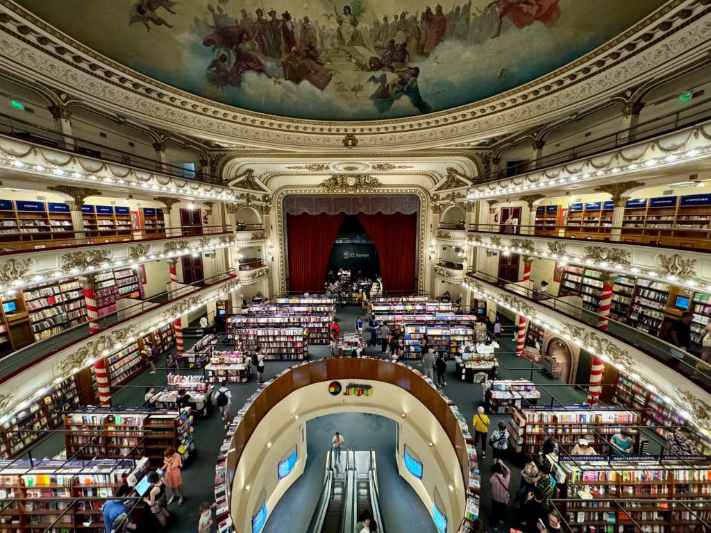 A bookstore inside a theater, with gorgeously laid out rows of books and a fresco on the ceiling.