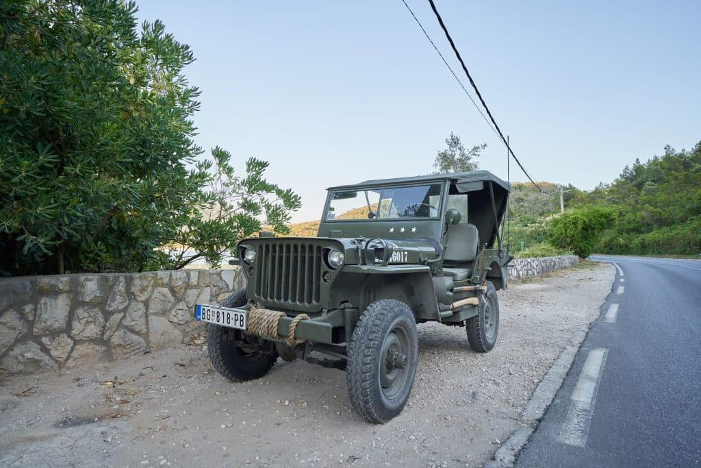 A dark green jeep parked on the side of the road in Montenegro.