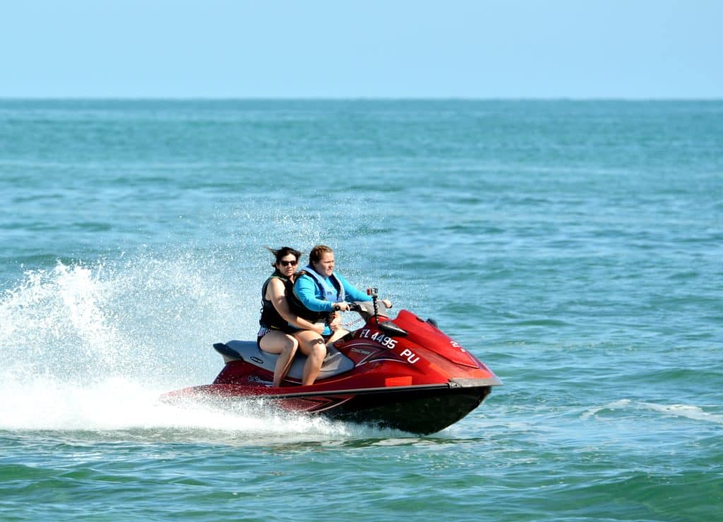 A man and a woman jet skiing on the open water near the Florida Keys.