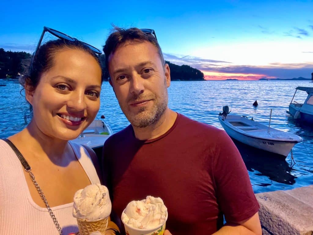 Kate and Charlie taking a selfie, eating ice cream in front of a blue and pink sunset on the sea.